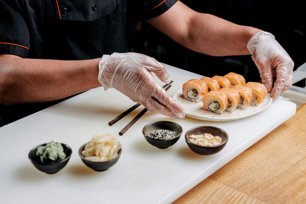 Chef arranging sushi platter with fresh ingredients in a restaurant setting.